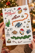 Merry Catmas sticker sheet held at an angle in a festive room